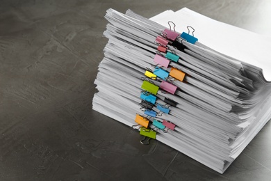 Photo of Stack of documents with binder clips on grey stone table. Space for text