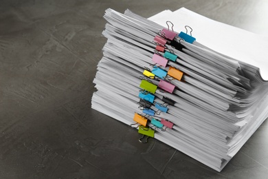 Stack of documents with binder clips on grey stone table. Space for text