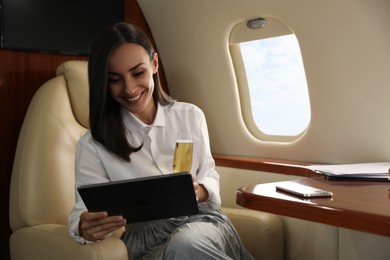 Photo of Woman with tablet and glass of champagne in airplane during flight
