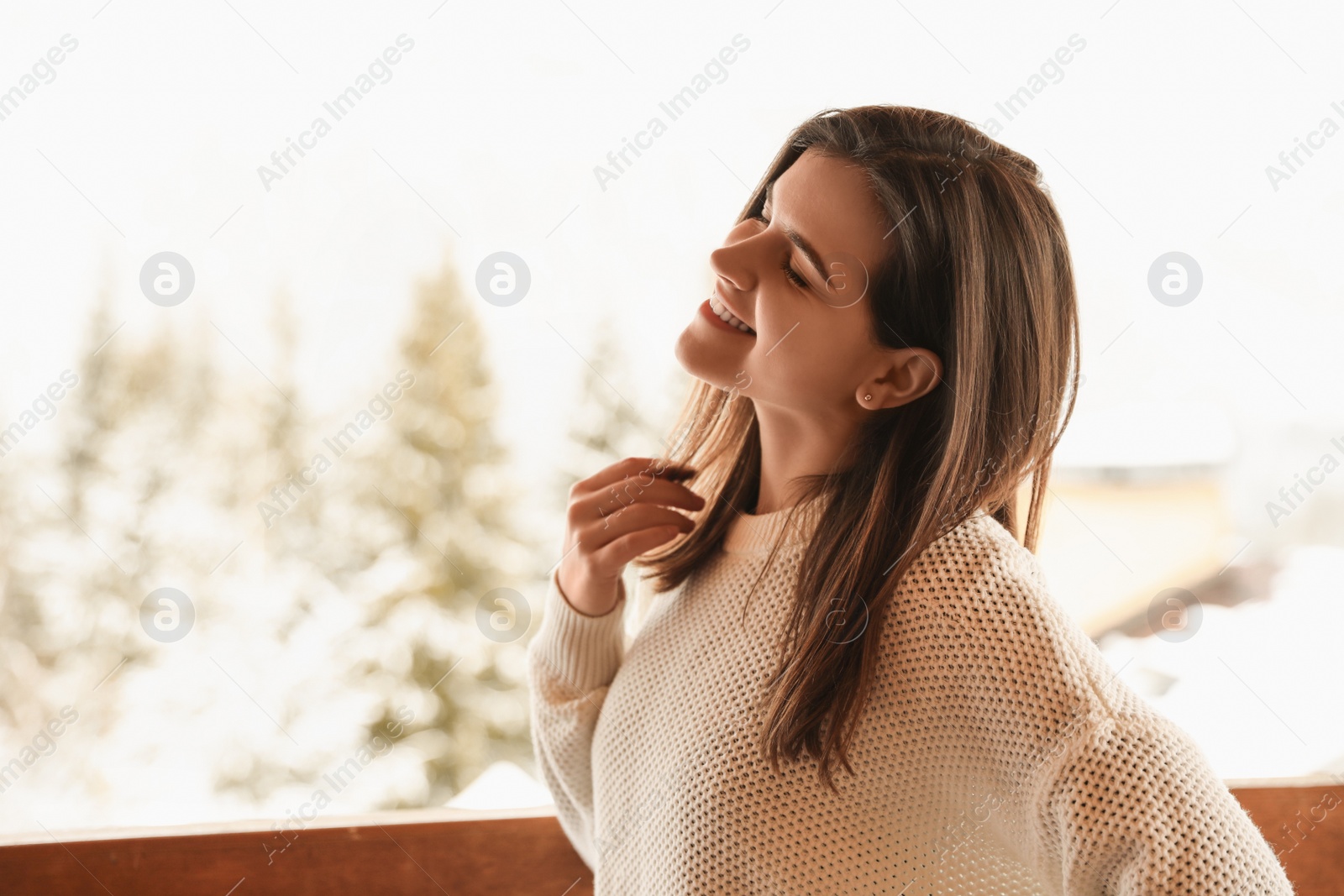 Photo of Pretty woman wearing warm sweater on terrace in winter