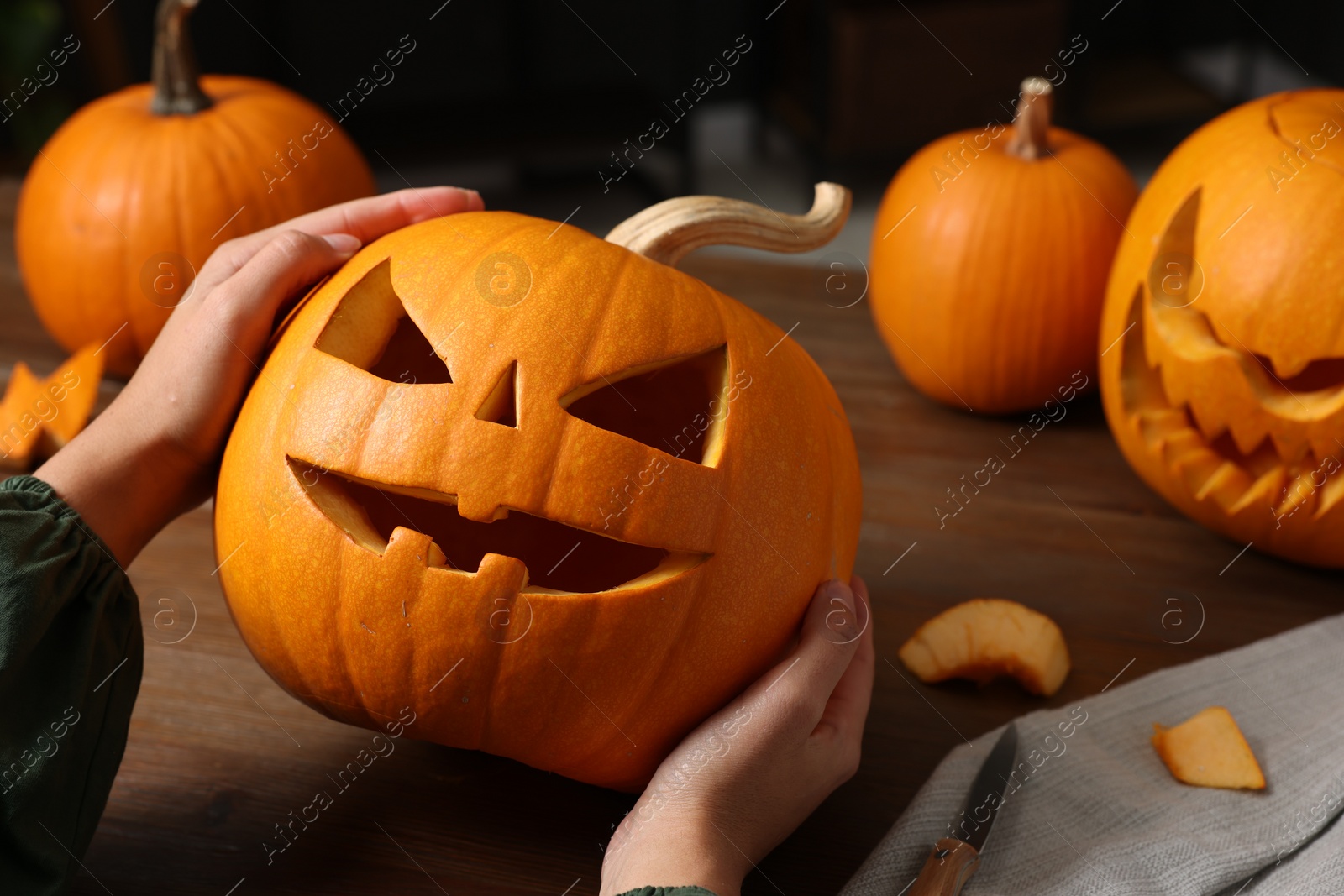 Photo of Woman holding carved pumpkin for Halloween at wooden table, closeup