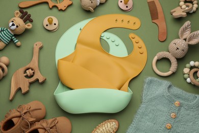 Photo of Flat lay composition with baby accessories and bibs on green background