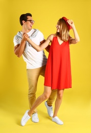 Photo of Beautiful young couple dancing on yellow background