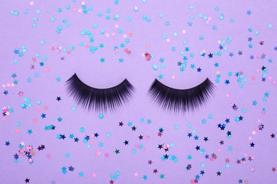 Photo of Flat lay composition with false eyelashes and shiny confetti on violet background