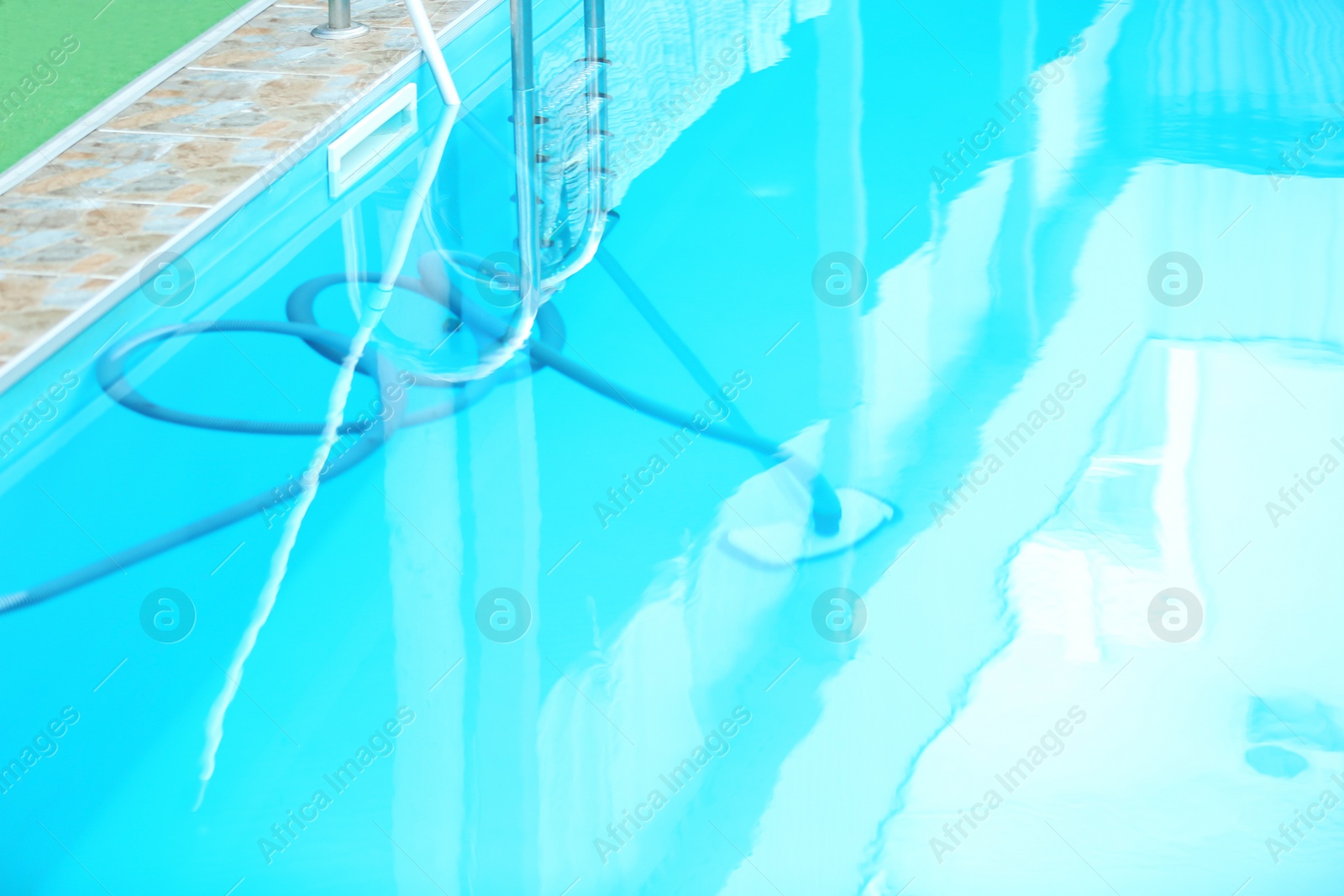 Photo of Cleaning outdoor pool with underwater vacuum, closeup