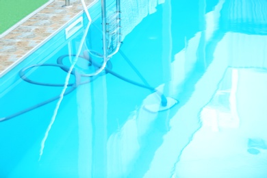 Photo of Cleaning outdoor pool with underwater vacuum, closeup