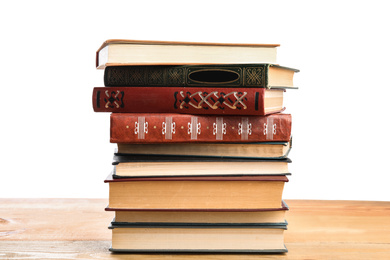 Stack of old vintage books on wooden table against white background