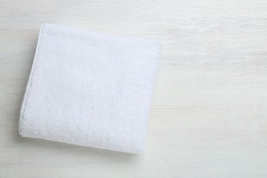 Photo of White terry towel on light wooden table, top view. Space for text