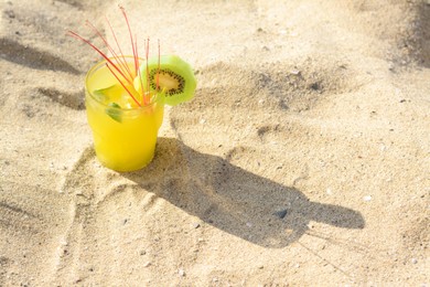 Photo of Glass of refreshing drink with kiwi and mint on sand. Space for text