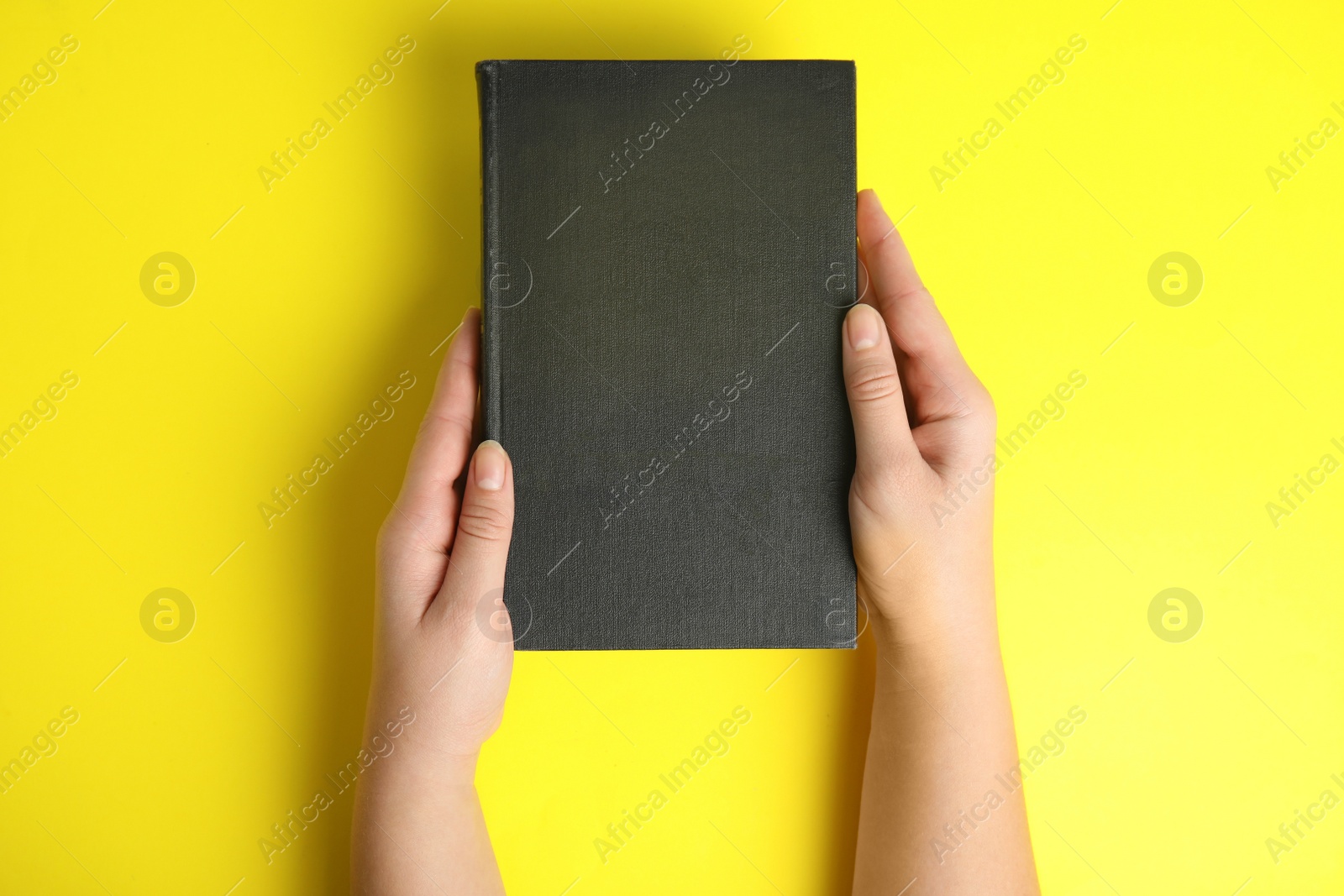 Photo of Woman with book on yellow background, top view. Space for design