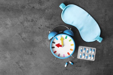 Photo of Sleeping mask, pills and alarm clock on grey background, flat lay. Insomnia treatment