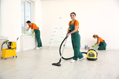 Photo of Team of professional janitors in uniforms cleaning room