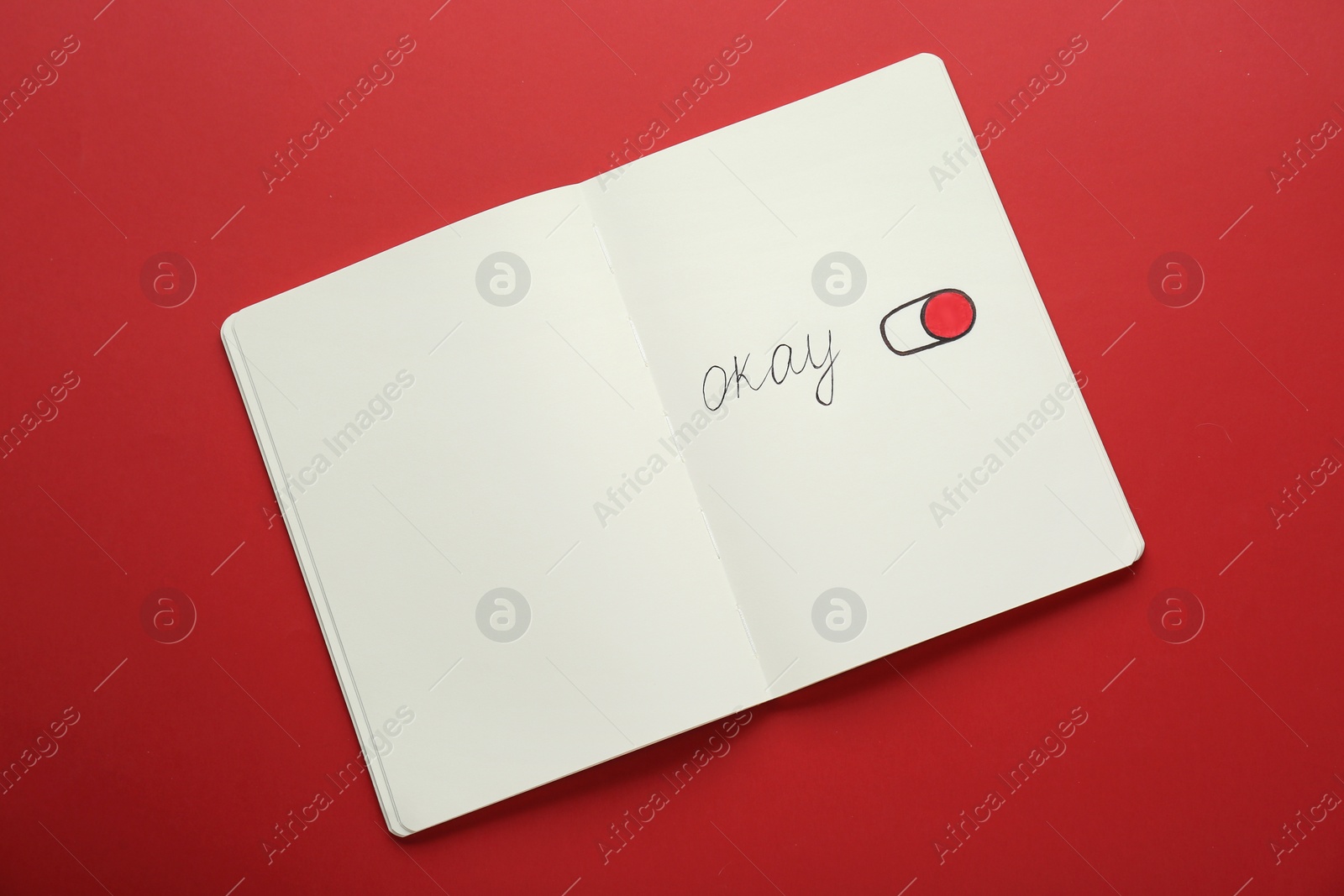 Photo of Notebook with word Okay and drawing of switch on button against red background, top view