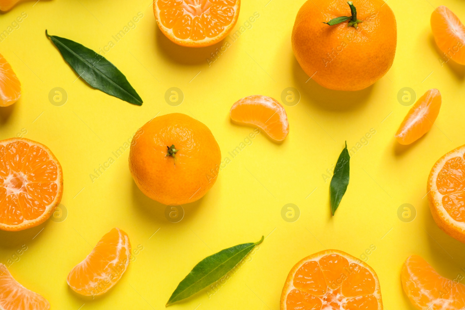 Photo of Flat lay composition with fresh ripe tangerines and leaves on yellow background. Citrus fruit