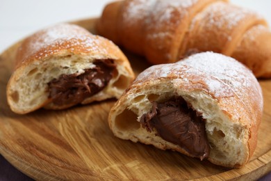 Fresh croissants with chocolate on wooden plate, closeup