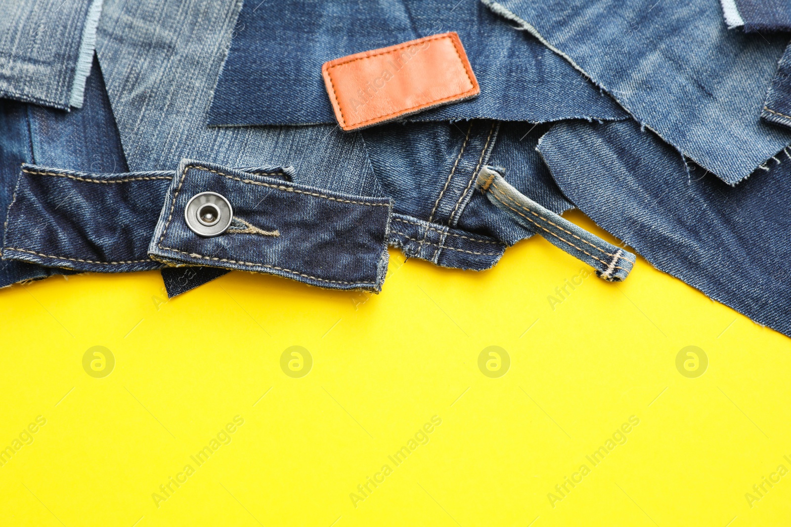 Photo of Flat lay composition with patches of old jeans on yellow background. Space for text