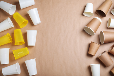 Photo of Flat lay composition with plastic and paper cups on beige background, space for text. Recycling concept