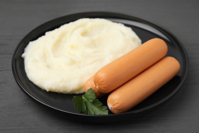 Photo of Delicious boiled sausages, mashed potato and parsley on grey wooden table, closeup