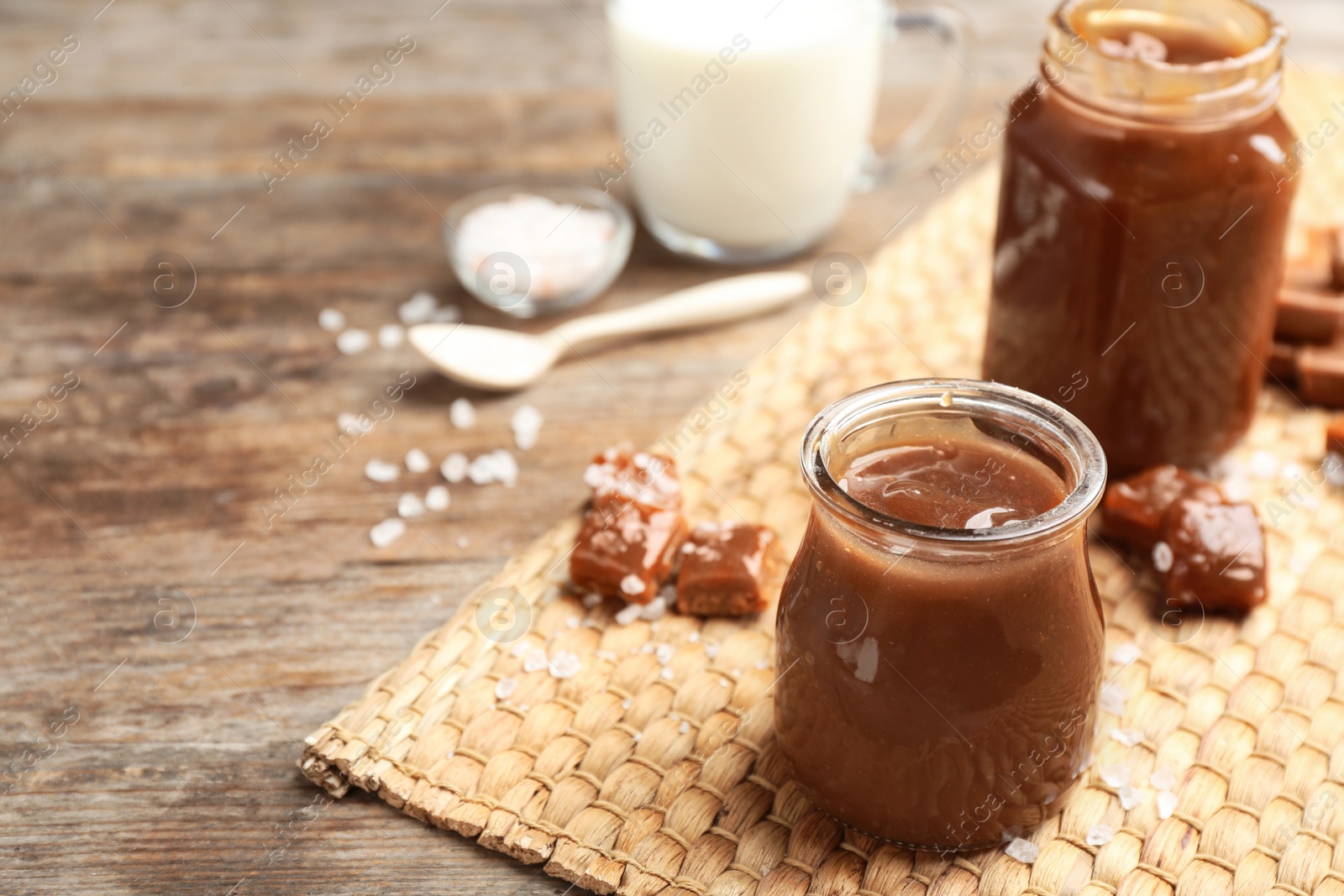 Photo of Jar of caramel sauce on wooden table. Space for text