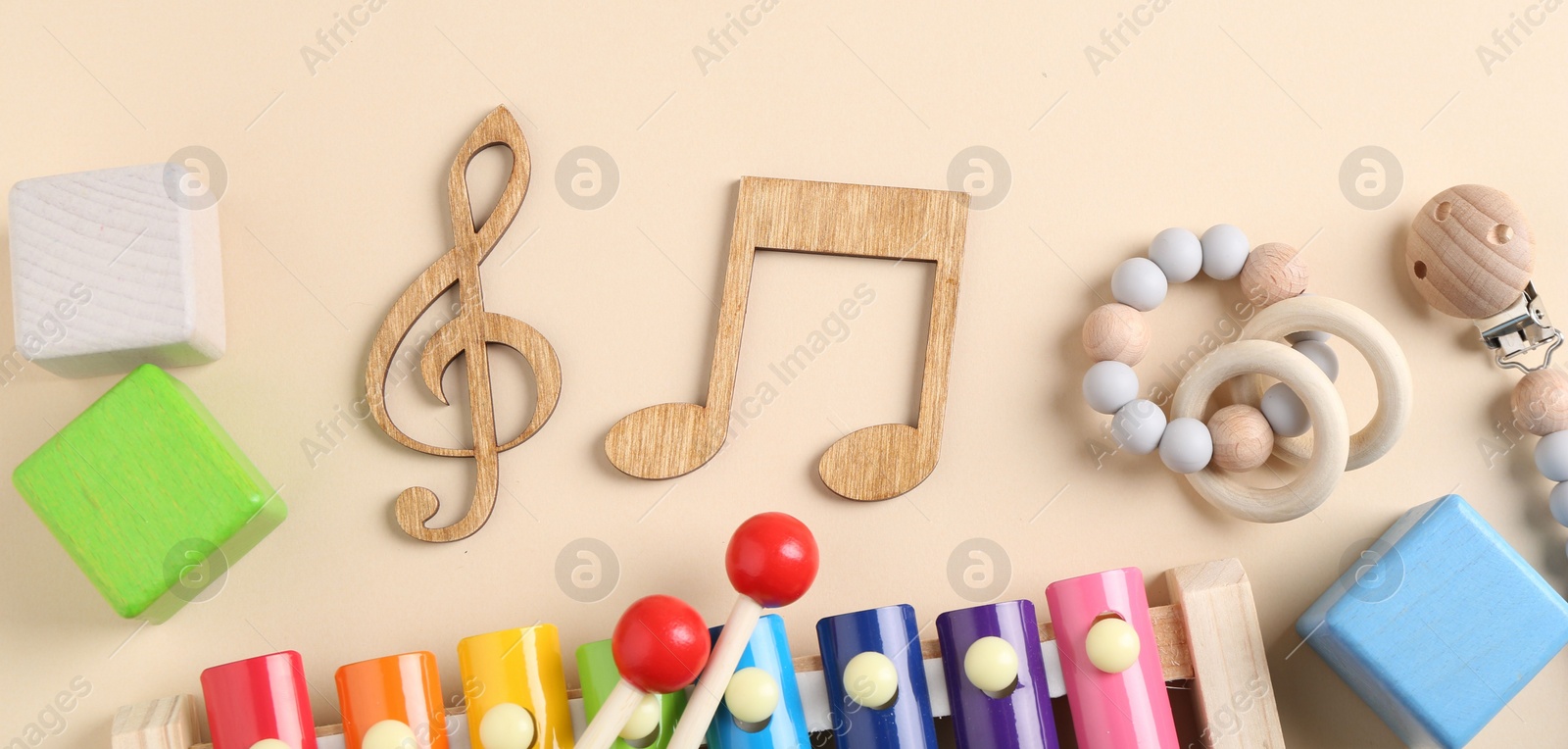 Photo of Baby song concept. Wooden notes, kids xylophone and toys on beige background, flat lay