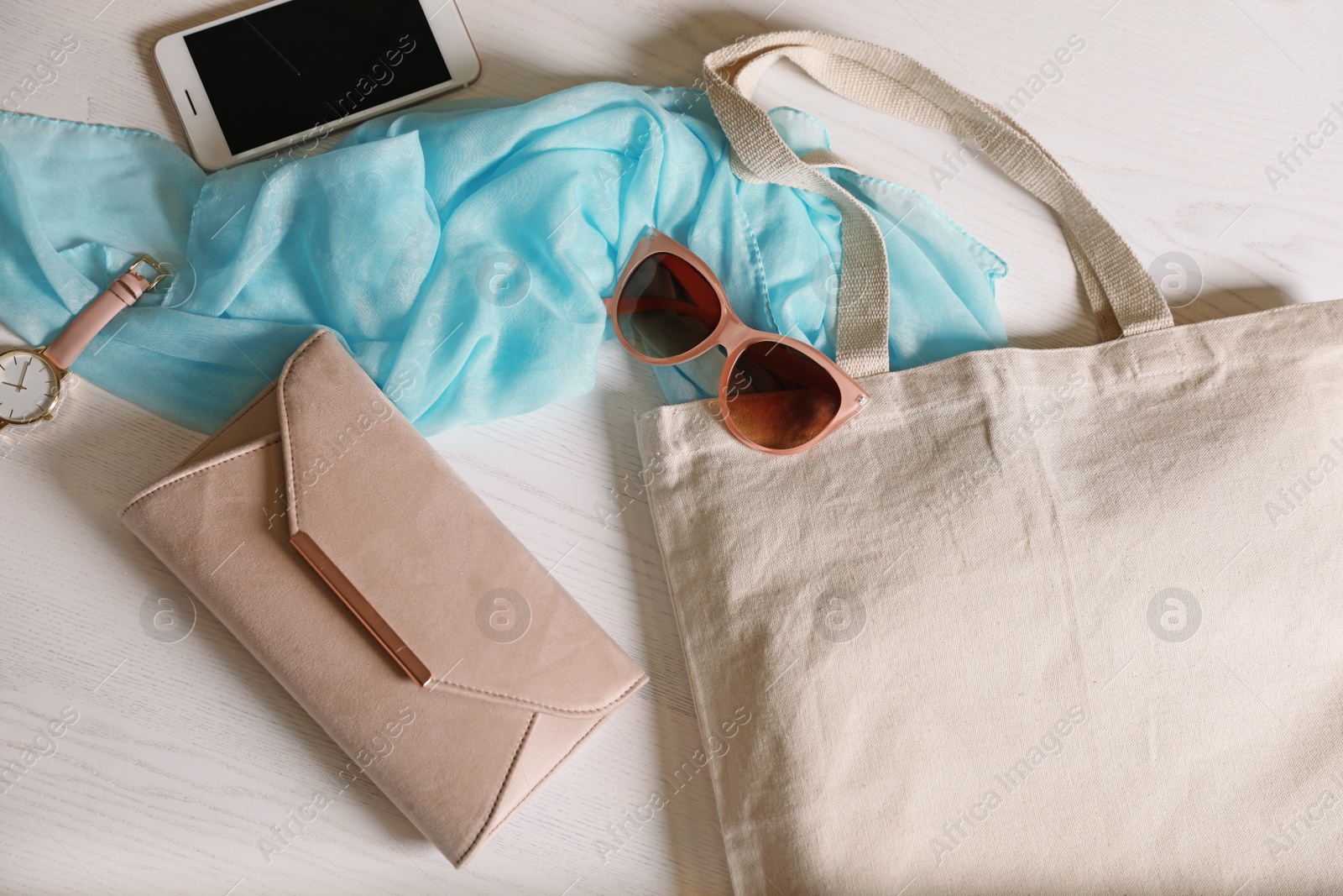 Photo of Flat lay composition with eco tote bag, smartphone and accessories on white wooden background. Space for design