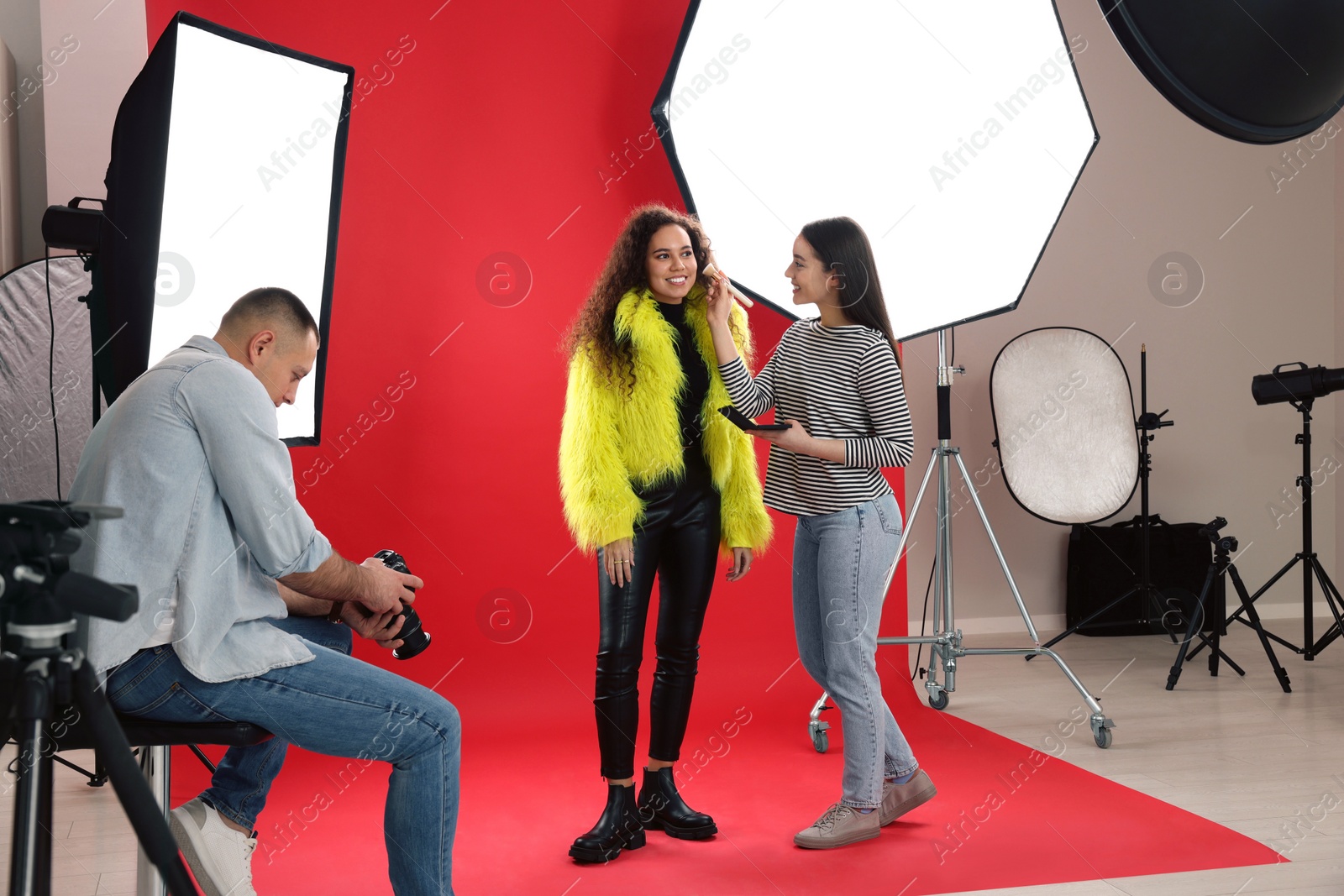 Photo of Professional photographer and makeup artist with model in studio