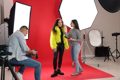 Professional photographer and makeup artist with model in studio