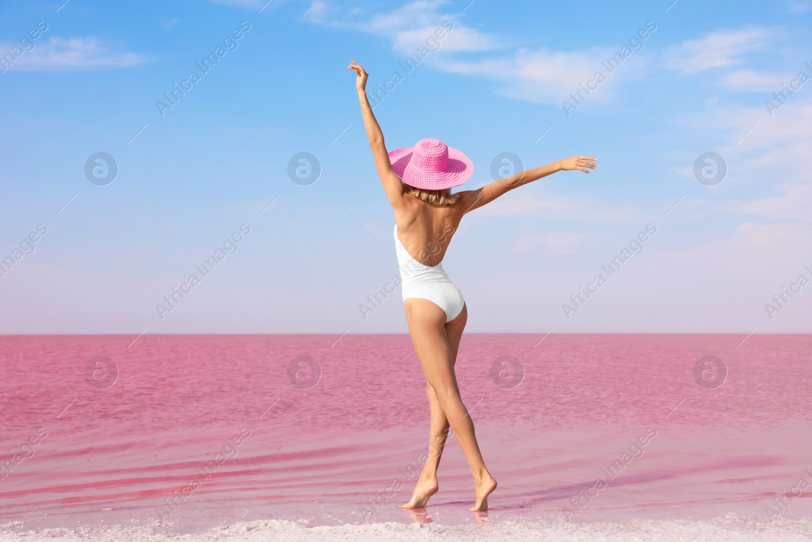 Photo of Beautiful woman in swimsuit posing near pink lake on sunny day