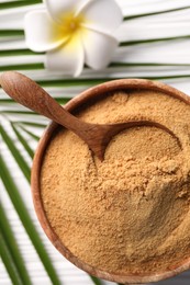 Coconut sugar and spoon in bowl on white wooden table, flat lay