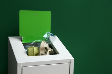 Photo of Overfilled trash bin on color background, space for text. Recycling concept