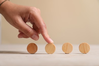 Photo of Choice concept. Woman choosing wooden circle among others at light table, closeup