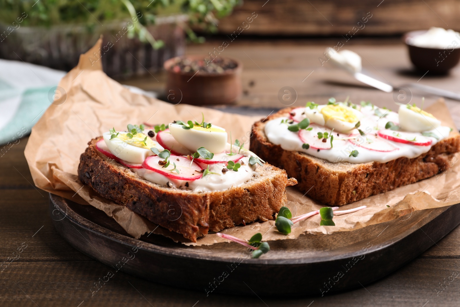 Photo of Delicious sandwiches with radish, egg, cream cheese and microgreens on wooden table