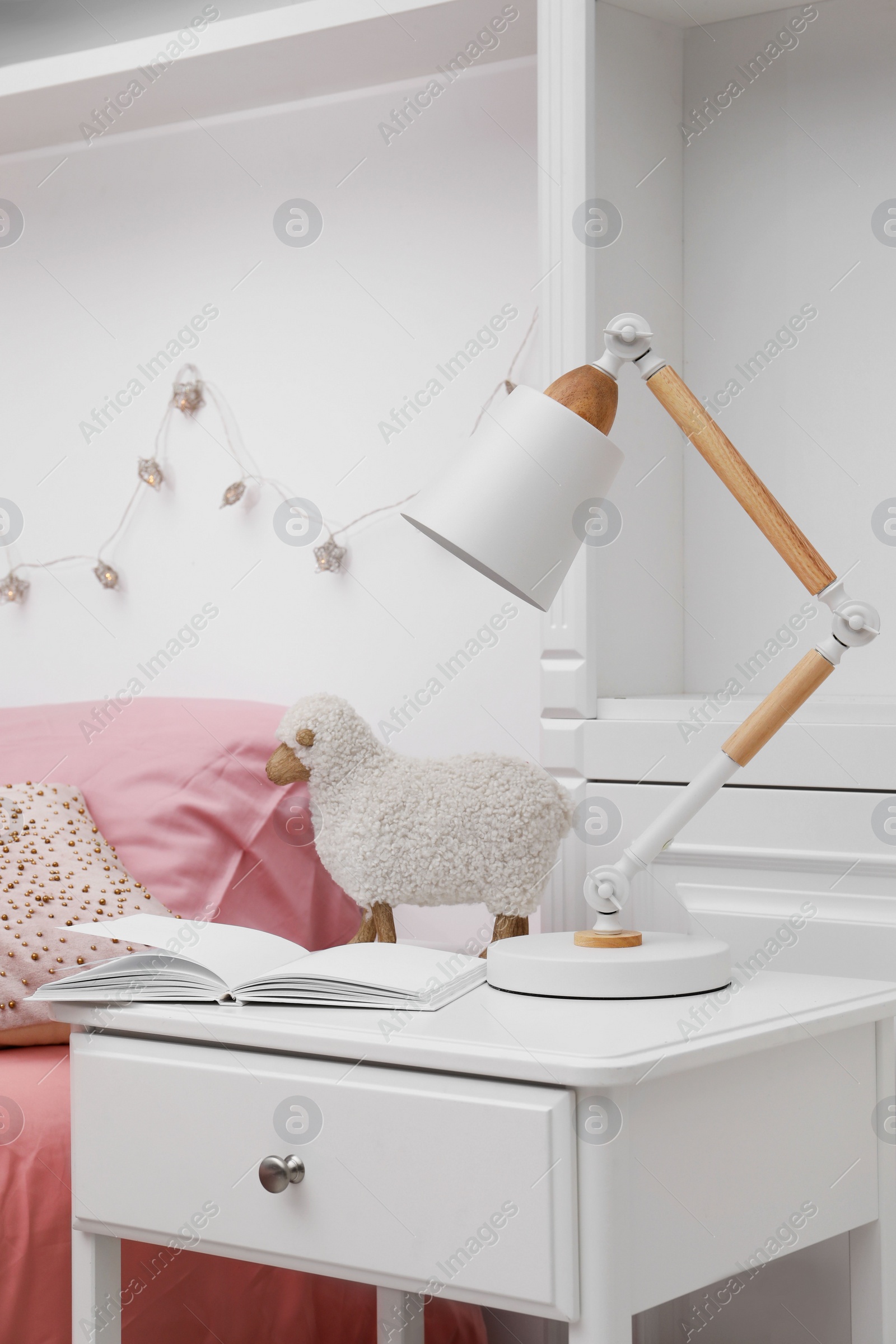 Photo of Lamp on white nightstand in cozy bedroom