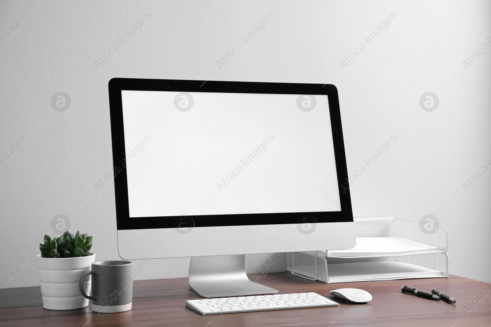 Photo of Comfortable workplace with modern computer on wooden table near white wall. Space for text