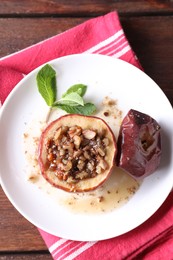 Photo of Tasty baked apple with nuts, honey and mint on wooden table, top view