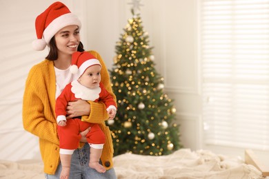 Happy young mother with her cute baby against blurred festive lights, space for text. Winter holiday