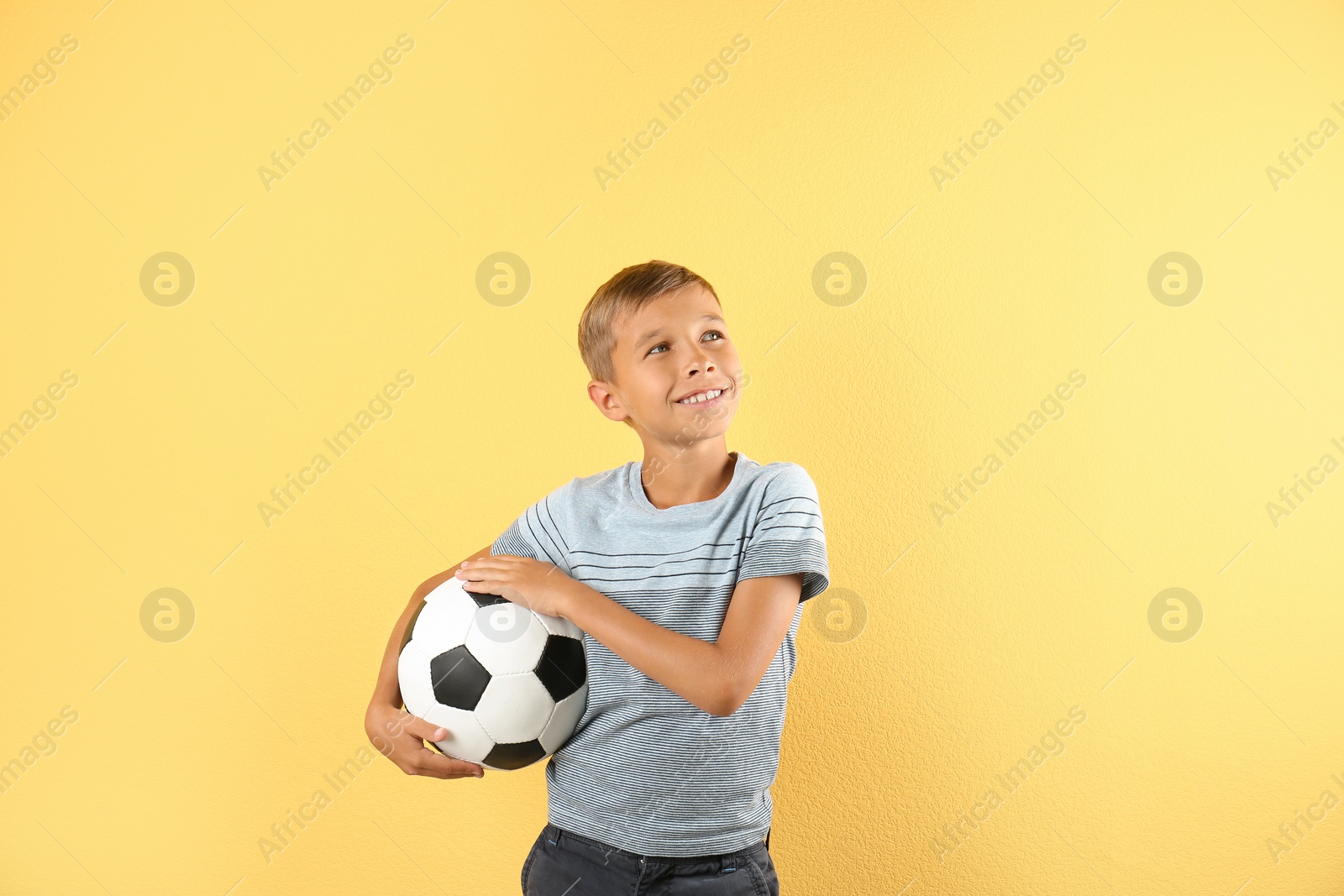 Photo of Adorable little boy with soccer ball on color background