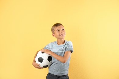 Photo of Adorable little boy with soccer ball on color background