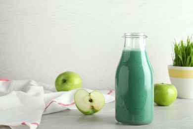 Photo of Composition with bottle of spirulina smoothie and fresh apples on table. Space for text