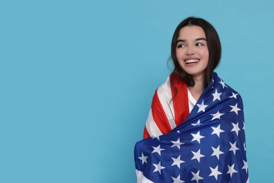 4th of July - Independence Day of USA. Happy girl with American flag on light blue background, space for text