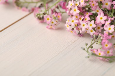 Photo of Beautiful Forget-me-not flowers on white wooden table, closeup. Space for text