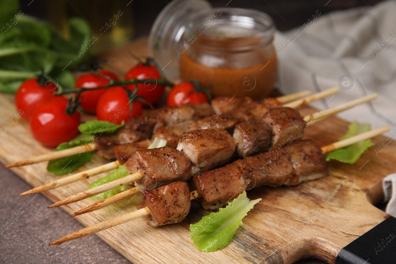 Photo of Tasty cooked marinated meat served with sauce and tomatoes on table, closeup