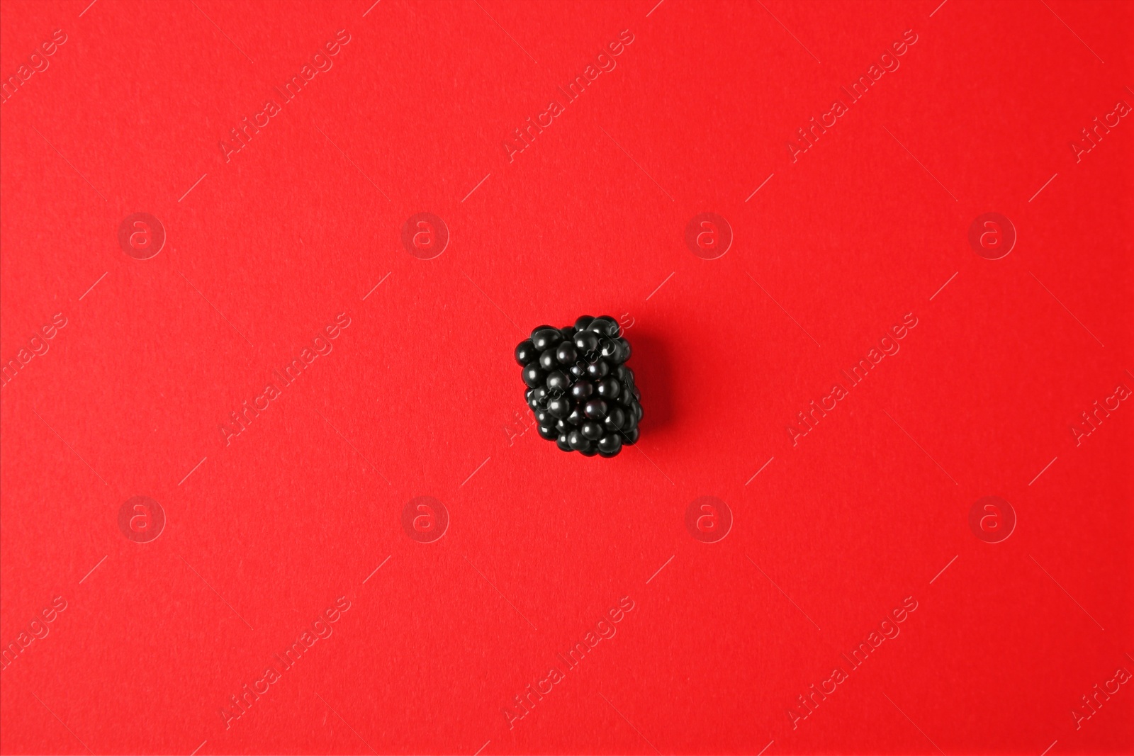 Photo of Tasty ripe blackberry on red background, top view