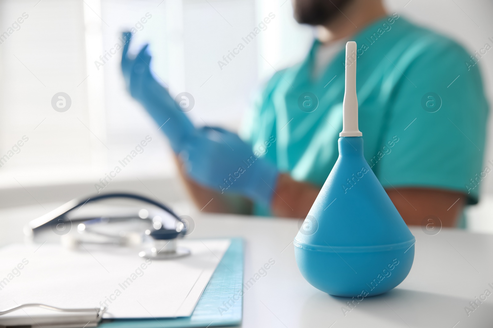 Photo of Doctor at table in hospital, focus on light blue enema