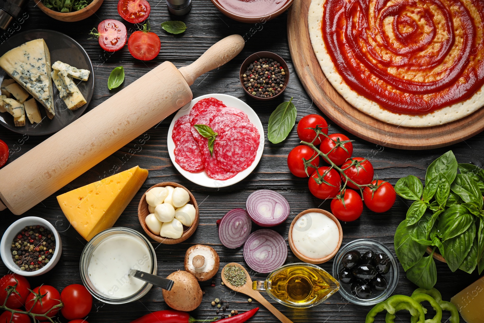 Photo of Flat lay composition with pizza crust and ingredients on dark wooden table