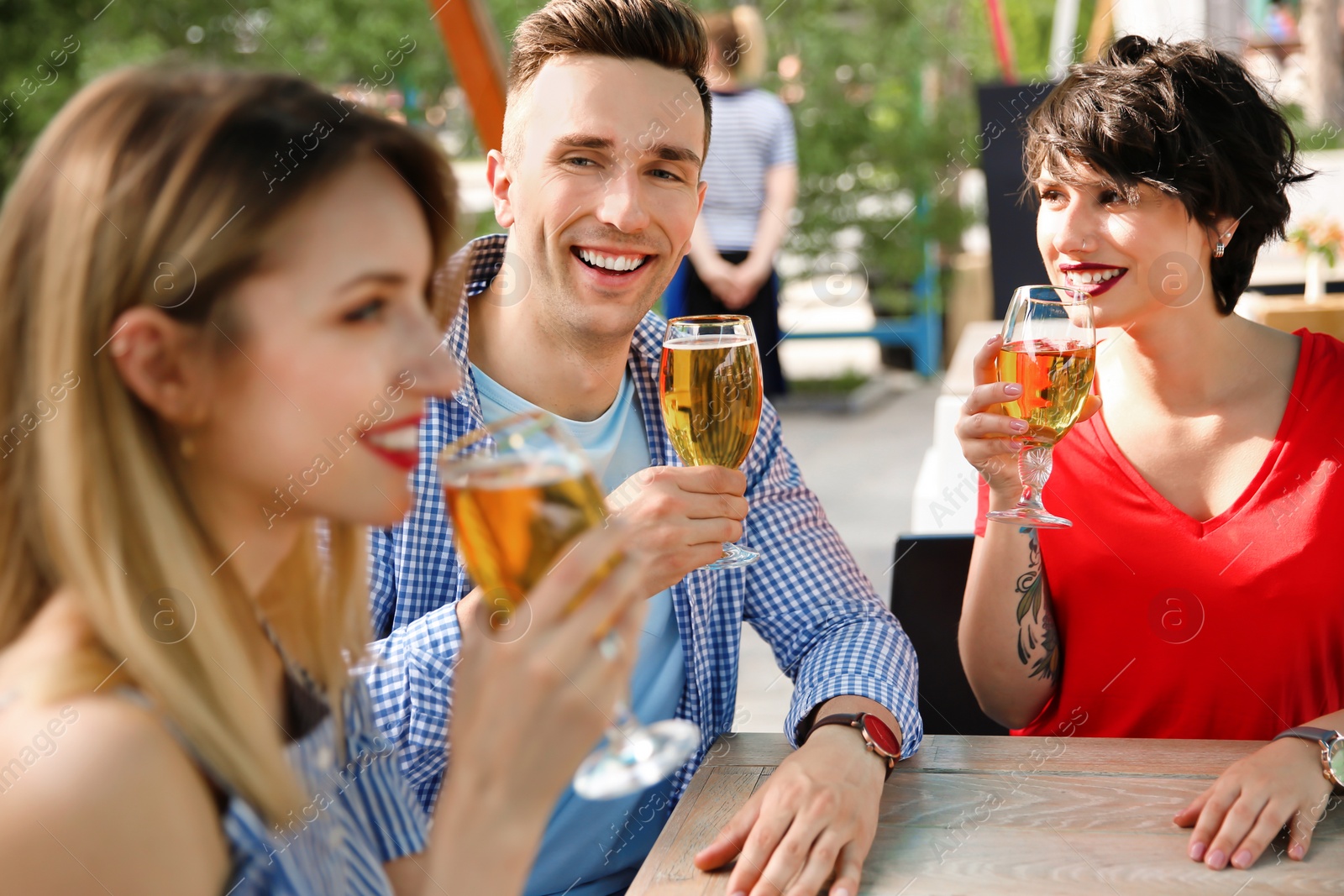 Photo of Young people with glasses of cold beer at table