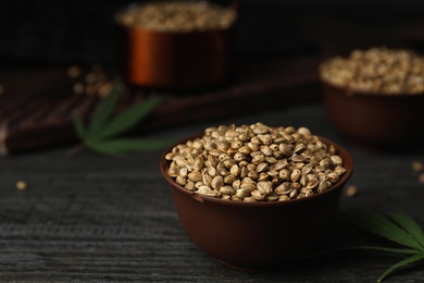 Photo of Organic hemp seeds in bowl on black wooden table