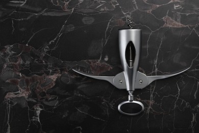 Photo of One wing corkscrew on black marble table, top view. Space for text