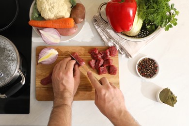 Photo of Man cutting meat to make bouillon at countertop, top view. Homemade recipe