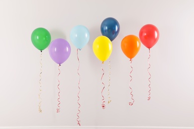 Photo of Different bright balloons on light background. Celebration time